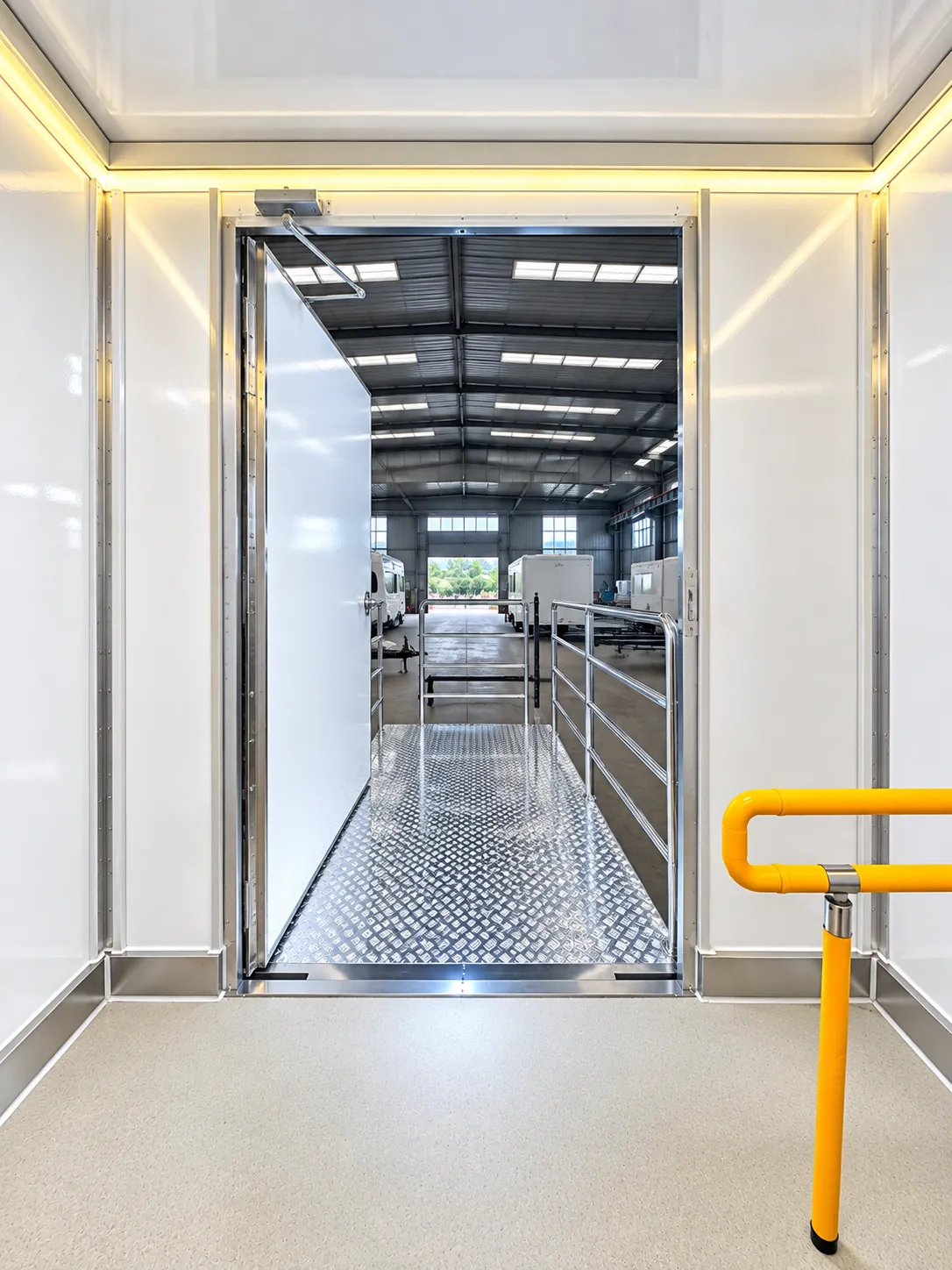 Wide entrance into a shower and restroom trailer with a handrail and grab bars