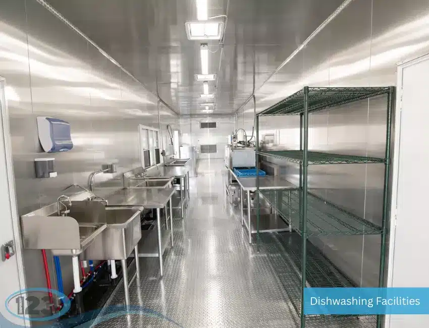 Interior of a commercial dishwashing trailer featuring dedicated sanitizing areas and stainless steel work surfaces.
