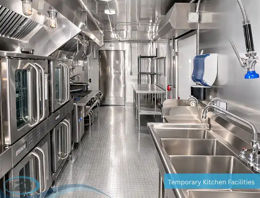 Fully equipped temporary commercial kitchen featuring stainless steel workstations, industrial appliances, and organized food preparation areas.